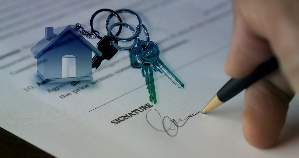 "Mano sosteniendo las llaves de una casa nueva, símbolo de compra de vivienda con respaldo legal."